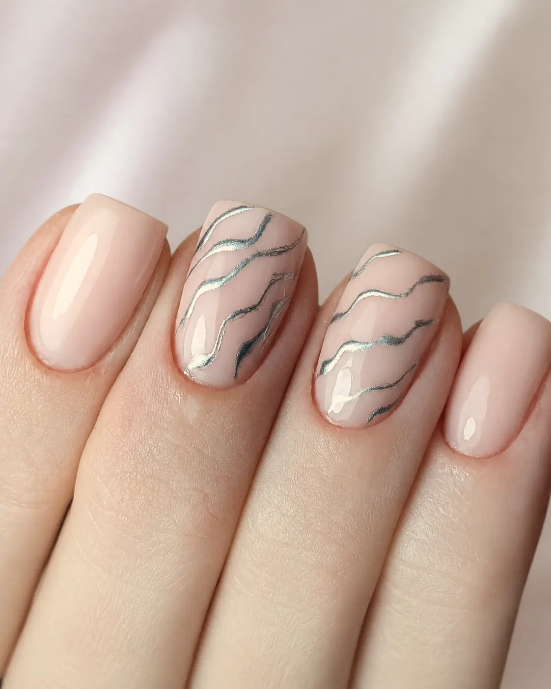 Nahaufnahme von zwei Nägeln in Nude mit gezeichneten Silberlinien.