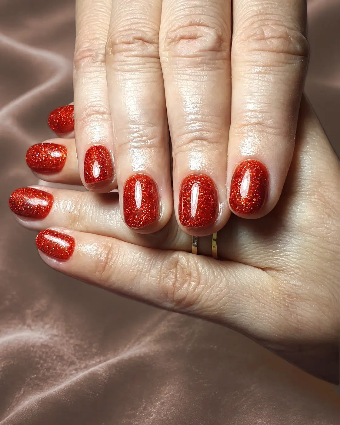 Runde Nägel in kräftigem Rot mit Glitzer.